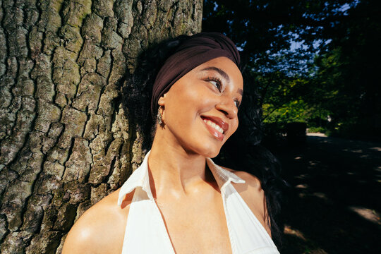 Woman Smiling Leaning Against Tree