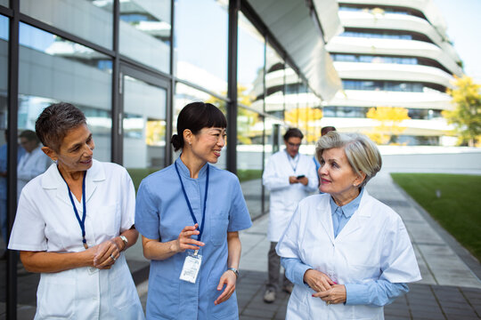 Women medical professionals walking and talking outside hospital