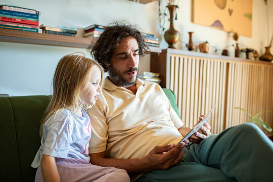 Man reading to child on tablet at home