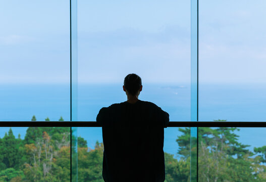 Copyspace Facing the Sea: Silhouette of a Woman by the French Window