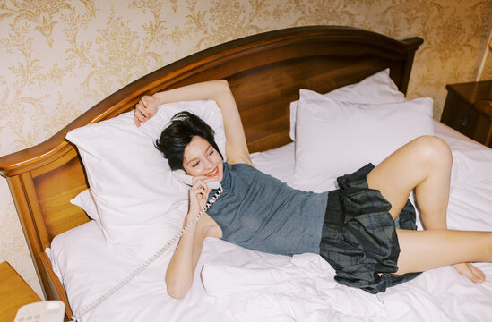 Woman Talking on the Phone While Lying on Bed in Cozy Room