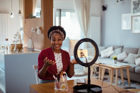 Smiling woman filming makeup tutorial at home