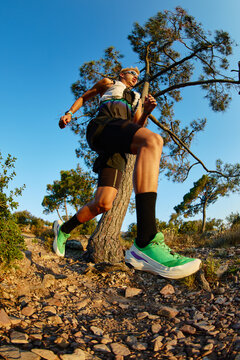 Runner on a trail surrounded by trees during sunset