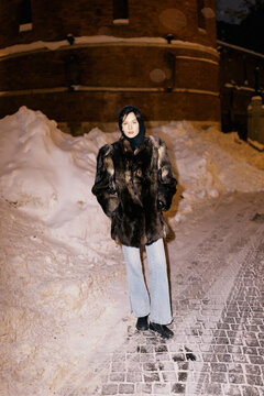Woman in Winter Outfit Standing Near Snow Mound at Night