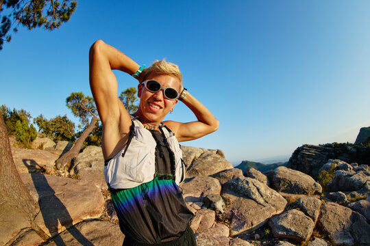 Hiking enthusiast poses on rock formation during sunny day