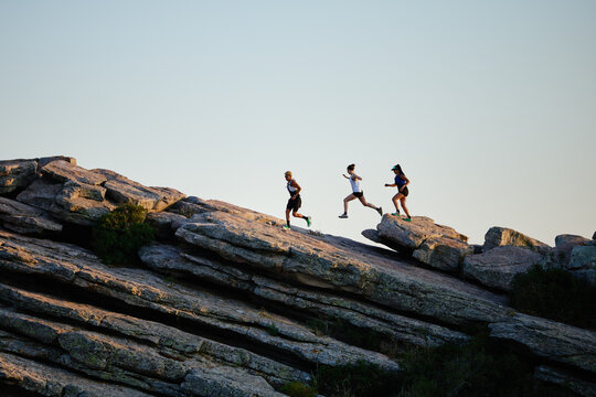 Group of people hiking on rocky terrain during sunset