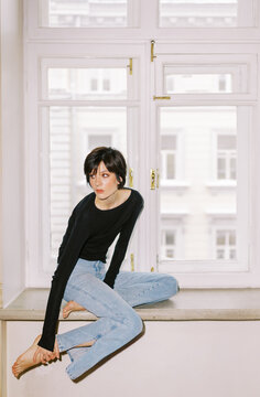 Woman Sitting on a Windowsill Looking out at the Street