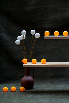 Still life with vase and white and orange balls on wooden shelves
