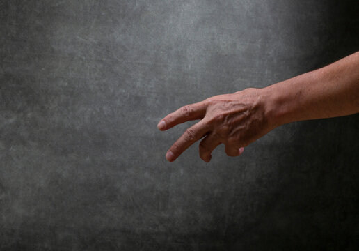 man's left hand raised against a dark background