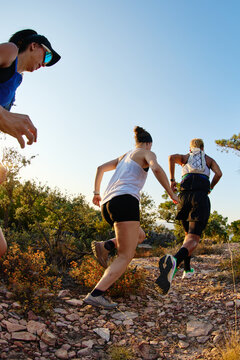 Runners participating in a trail run at sunset in a natural sett