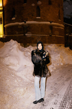 Woman in Winter Outfit Standing Near Snow Mound at Night