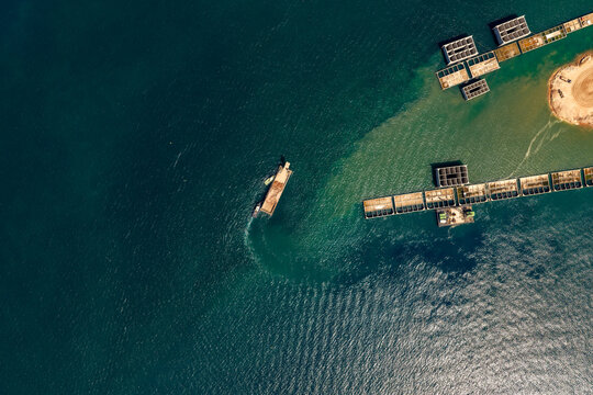 Tugboat pulling barge near port expanding development.