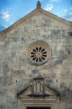 Stone fa&ccedil;ade of Our Lady of the Rocks Church near Perast, Montenegro, featuring a limestone rose window, classical entrance portal, and rustic Adriatic coastal stonework.