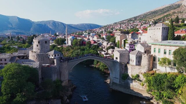 Aerial view of the historic Old Bridge (Stari Most) surrounded by traditional stone buildings, historic towers, and red-roofed houses in the old town at dusk in Mostar, Bosnia and Herzegovina