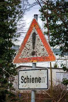 Rusty warning sign with exclamation mark and German text "Schienen" meaning "tracks"