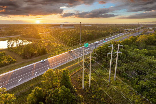 Steel high voltage towers with electric lines transmitting power above highway traffic. Concept of overlapping infrastructure systems.