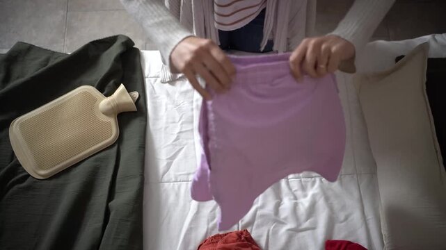Close-up of a woman&rsquo;s hands folding clothes before storing them in her closet. Concept of home organization, clothing care, and everyday household routines.