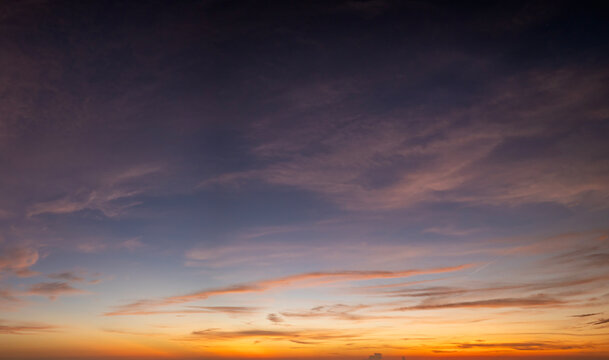 Sunset sky with bright colorful orange and yellow clouds. Panoramic skyscape