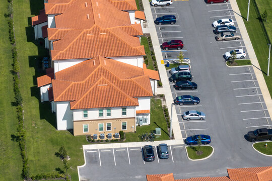 Top-down view of residential parking lot with vehicles near Florida apartment buildings, highlighting suburban condo housing in America