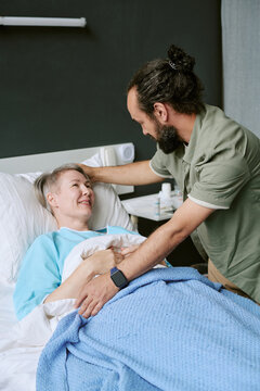 Vertical shot of middle aged Caucasian man supporting hospitalized middle aged Caucasian woman in clinic. Healthcare concept suitable for medical insurance advertising