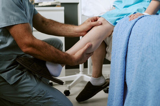 Caucasian male doctor examining leg of senior Caucasian patient in clinic. Concept representing orthopedic rehabilitation, perfect for physical therapy advertising