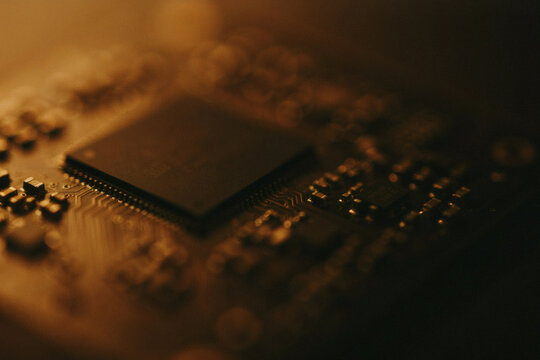 Close Up Macro Shot Of A Microchip Processor Mounted On A Circuit Board Under Warm Golden Lighting