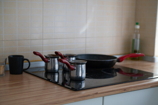 Cookware sits on a kitchen stove beside a tiled wall during daytime