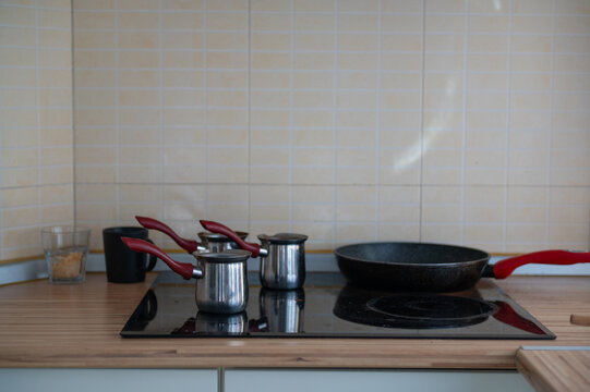 Cookware arranged on a kitchen stove beside tiled walls during the day