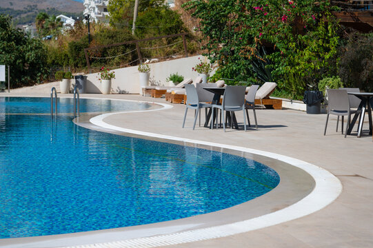 Outdoor swimming pool with patio tables and chairs at a hillside hotel