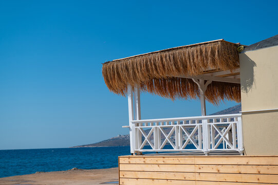 Thatched beach pavilion with white railings beside the sea under a clear sky