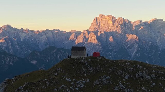 Aerial 3x telephoto view of Rifugio Tiziano and Bivacco Toso at sunset in the Marmarole Dolomites, with Tre Cime di Lavaredo in the background.