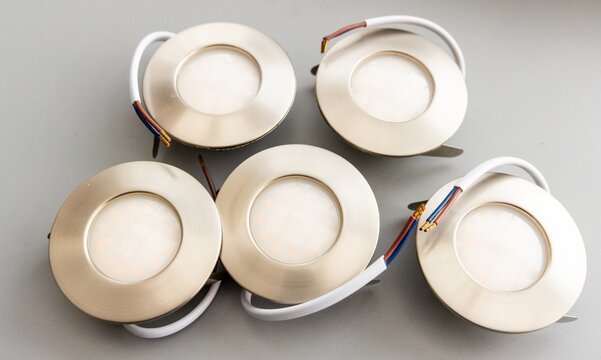 Five Modern Brushed Metal LED Recessed Downlights with Wires on Gray Background