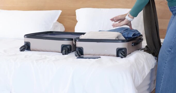 woman packing suitcase on bed, folding jeans, fixing scarf, checking phone and zipper, copy space