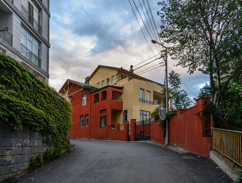 September 23, 2026, Tbilisi, Georgia: Road curving past yellow and red house facade