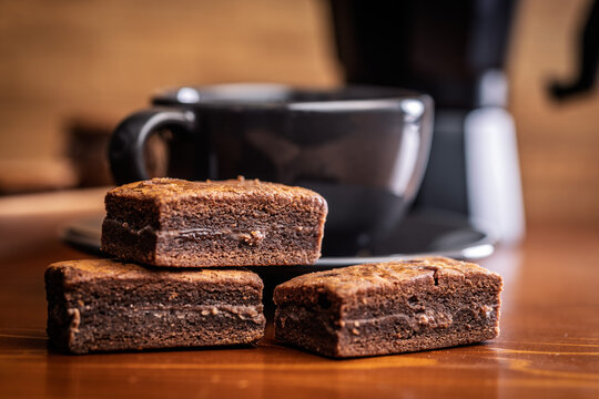 Stacked Chocolate Brownies With Coffee Mug In Cozy Cafe Setting, Close-Up Dessert Photo