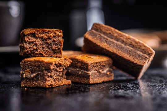 Close-Up Stack Of Chewy Chocolate Brownies With Crumbly Texture On Dark Surface
