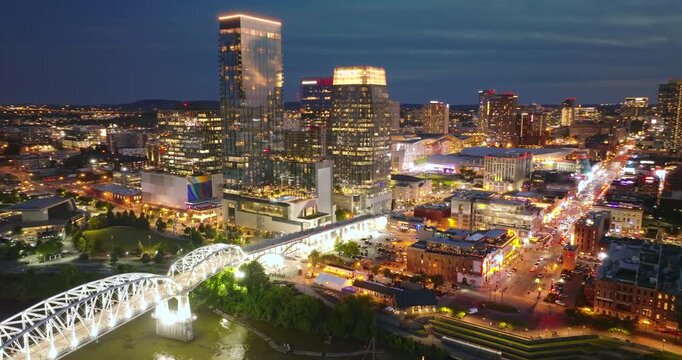 Nashville city urban environment in Tennessee, USA at night. View from above of skyscraper district with riverfront bridge in evening atmosphere.