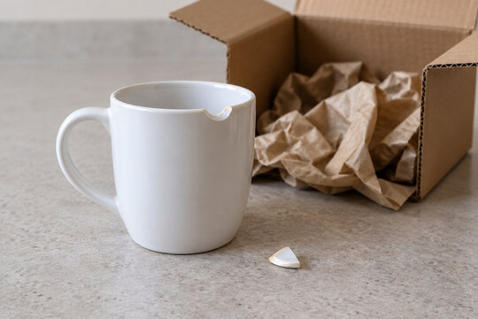 Chipped ceramic mug beside an open shipping box