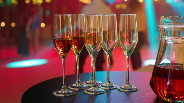 Golden bokeh behind five crystal champagne flutes and carafe. Warm evening banquet hospitality