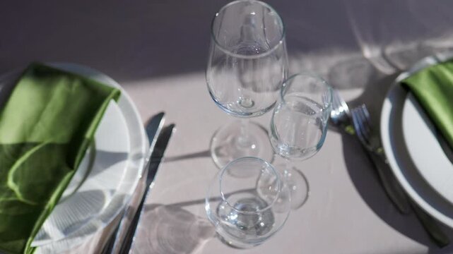 Overhead view of crystal wineglasses and green napkins on table. Fine dining banquet setup
