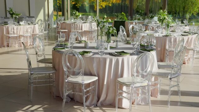 Banquet hall interior with round tables and transparent chairs. Panoramic windows in event venue