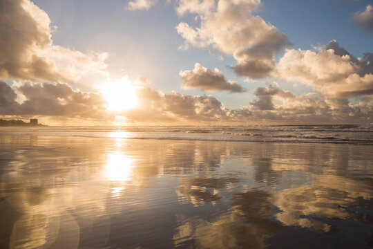 Sunset reflecting on an ocean beach with beautiful heavenly light 