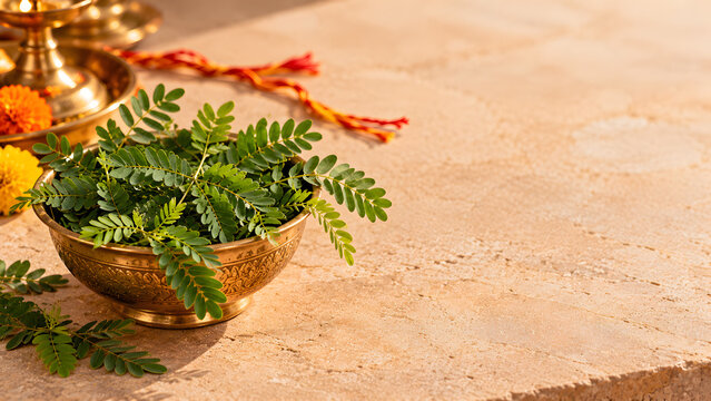 Traditional Indian Diwali decoration featuring sacred Banni leaves in a golden brass bowl with marigold flowers and a brass oil lamp
