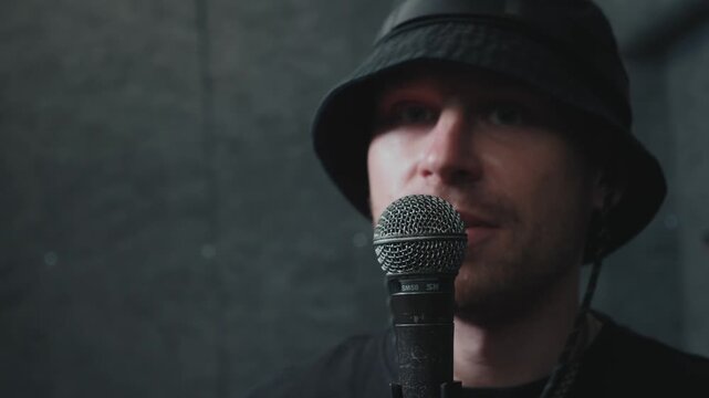 Male vocalist delivering lyrics into microphone during music rehearsal, expressive performance and contemporary urban style.