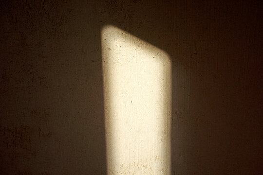 Close-up vertical illuminated panel creates bright rectangle and crisp shadow on rough concrete wall, offering minimalist warm-toned background for design and presentation layouts.