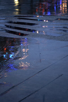 The street corner with rain and neon lights, the ground reflects blue light.