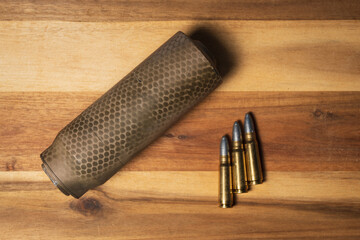 Sound suppressor and subsonic 762x39 ammunition with solid lead cast bullets lying on wooden surface, showcasing tactical shooting gear and custom reloading © Dmitri