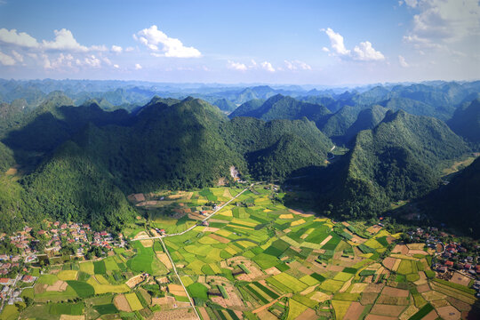 Aerial view of Bac Son valley with vibrant green rice paddies, patchwork fields, and dramatic limestone karst mountains Bac Son, Lang Son, Vietnam.