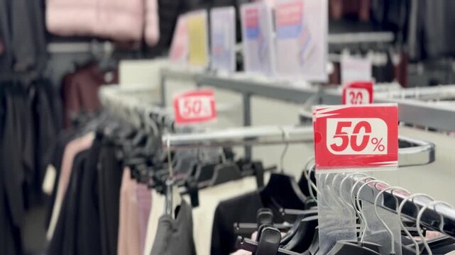 50 percent off clothing sale &mdash; red discount sign on clothes rack in fashion store