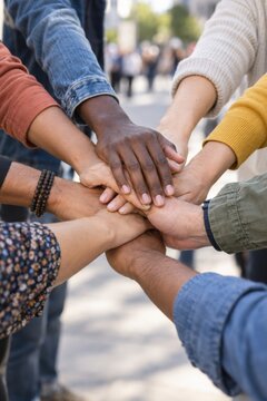Diverse group stacking hands together in unity, teamwork, inclusion and human rights support